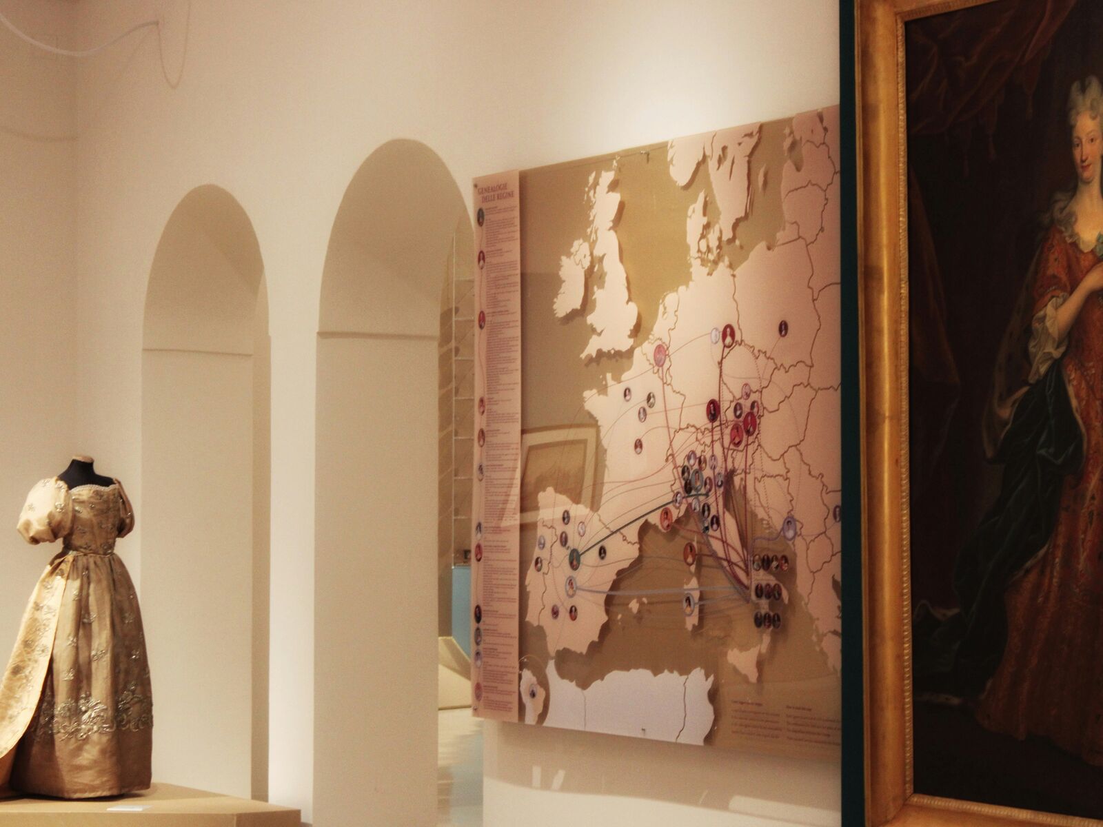 A museum exhibition with a period gown, a map of Europe and a portrait
